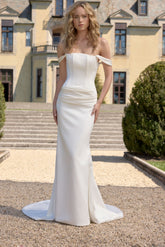Woman in a white strapless gown standing in front of a classical building.