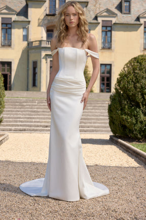 Woman in a white strapless gown standing in front of a classical building.