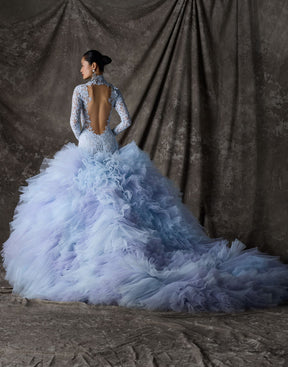 Blue lace and tulle ballgown with open back and long train against a textured brown backdrop